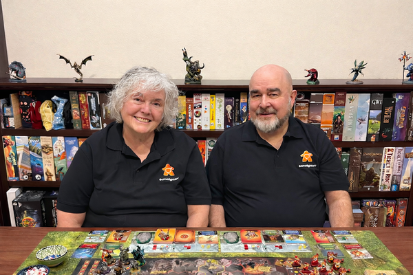 Dallan and Solveig Quass at their gaming table, surrounded by board games and miniatures